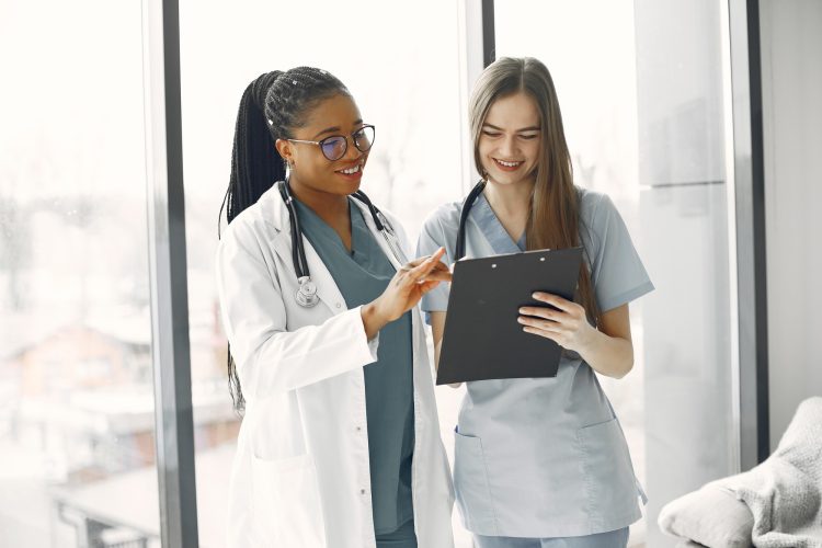 A female doctor and a female nurse talking over a patient's diagnosis with a clipboard