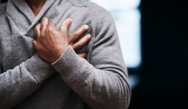 a black man wearing a sweater holds his hands over his chest