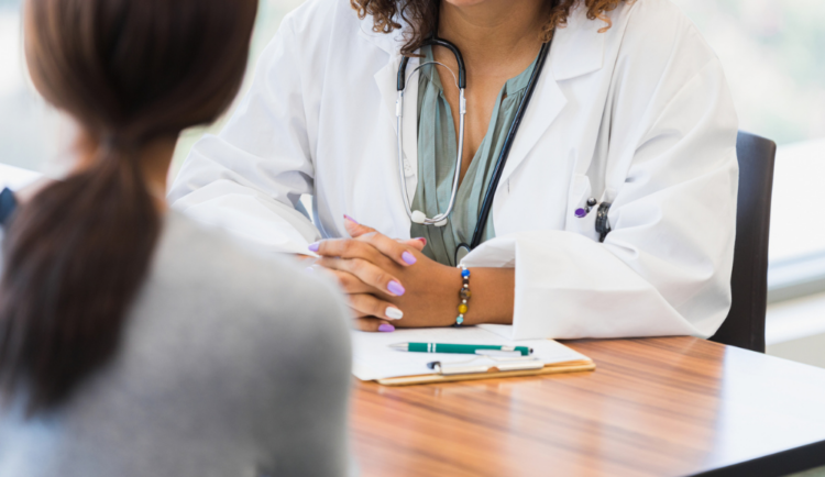 a closeup of a doctor speaking to a patient, we only see their hands and chests at a desk