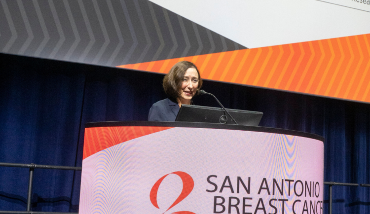 Dr. Judy Garber speaks at SABCS on a stage behind a podium