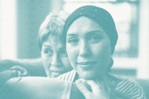 a woman in a head scarf sits with her older mom illustrative of a breast cancer diagnosis